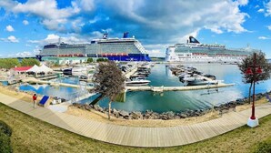 A marina with two large cruise ships docked, a wooden boardwalk, and a small docked boat. - Luxury Waterfront Marina Condo in Downtown (Charlottetown)
