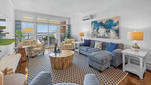 A spacious living area with a large window, a round coffee table, and a sofa set. - Luxury Waterfront Marina Condo in Downtown (Charlottetown)
