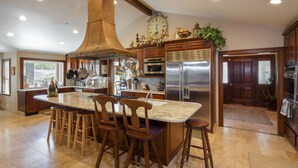 A spacious kitchen with a large island, wooden bar stools, stainless steel appliances, and a decorative clock on the wall. - Fantastic Vacation Retreat, Family Reunions , and Private Pool! (Salinas)