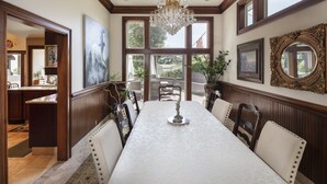 A dining room with a long table, chairs, a chandelier, and large windows. - Fantastic Vacation Retreat, Family Reunions , and Private Pool! (Salinas)