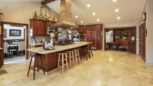 A spacious kitchen with a large island, wooden cabinets, and a prominent chimney. - Fantastic Vacation Retreat, Family Reunions , and Private Pool! (Salinas)