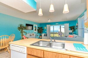A modern kitchen with a built-in dishwasher, a large sink, and a dining area with wooden chairs.