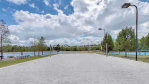 Una cancha de voleibol al aire libre con una red, bancos y un farol.