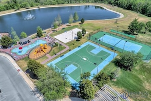 Vista aérea de un parque con cancha de baloncesto, parque infantil y un lago.