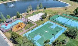 Luchtbeeld van een park met een basketbalveld, een speeltuin en een meer.