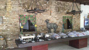 A buffet setup with a variety of food items, a decorative horse statue, and a brick wall backdrop. - Your rest in style! (GRAVATÁ)