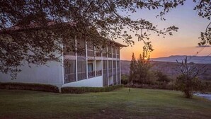 A modern building with large windows and a balcony, surrounded by a well-maintained lawn and trees. - Your rest in style! (GRAVATÁ)