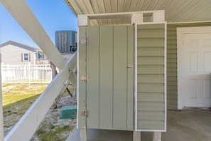 Un cuarto de servicio con una puerta verde, una puerta blanca y una unidad de aire acondicionado metálico en el exterior.