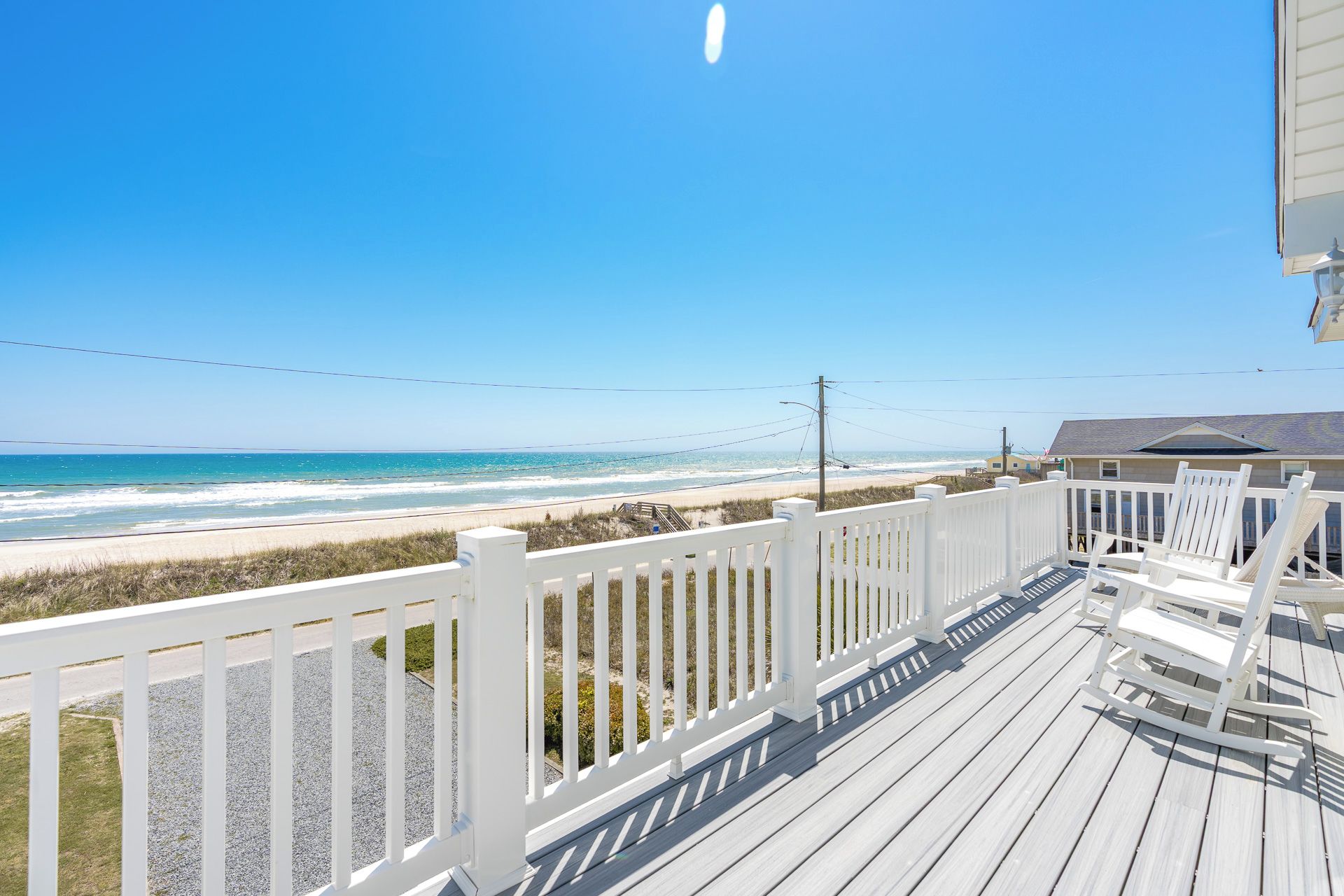 Une terrasse en bois avec des balustrades blanches donnant sur une plage.