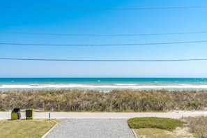 A coastal road with a clear view of the ocean and beach vegetation.
