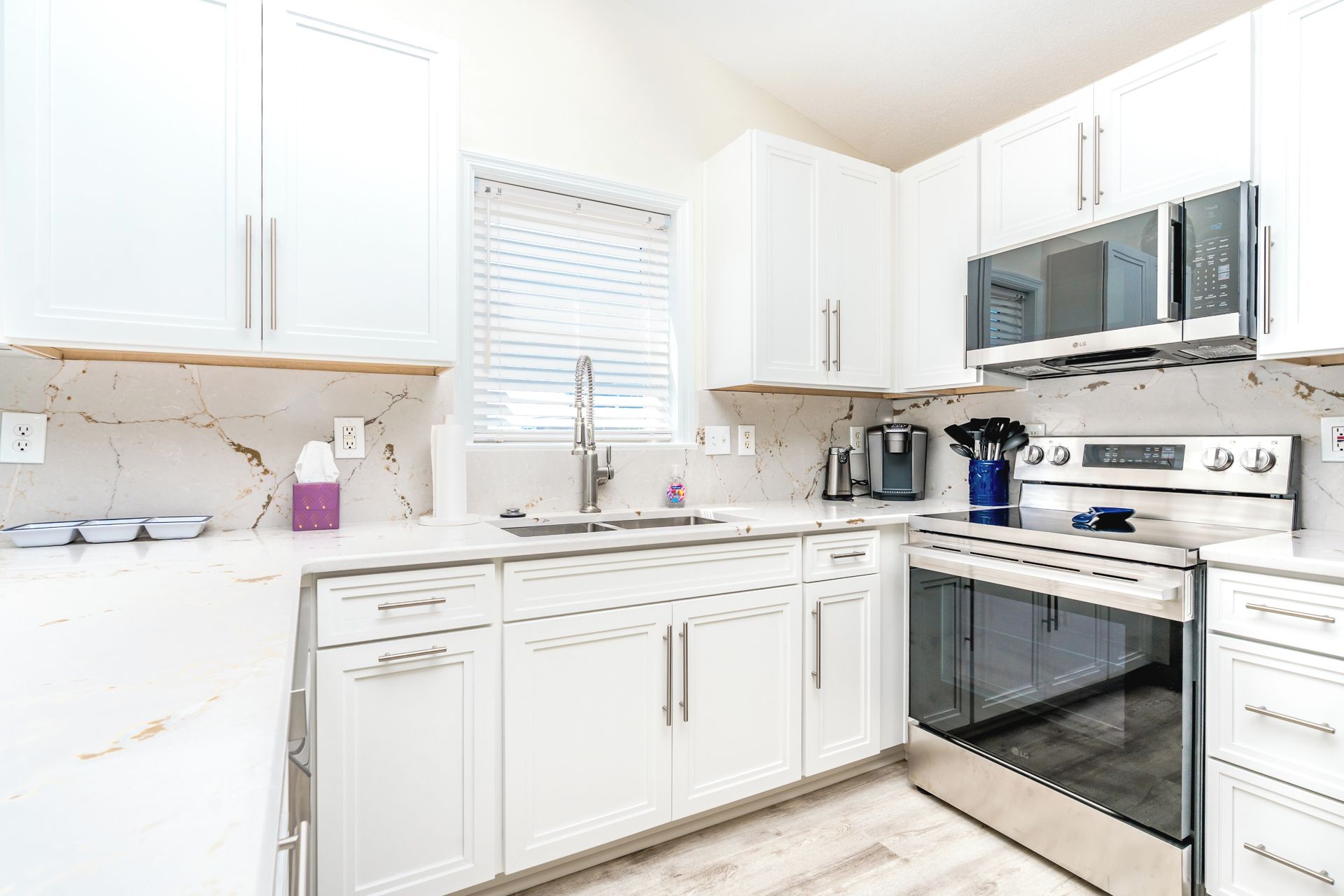 A modern kitchen with white cabinets, a stainless steel range, and a microwave.