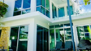 A modern two-story building with large windows, a balcony, and a pool area with lounge chairs. - Welcome to the Lucky Penny! (Ocean Park)