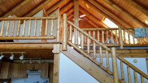 Un escalier en bois, doté d’une rampe, mène à une mezzanine.