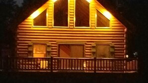 Une cabane en rondins avec une véranda et de grandes fenêtres.