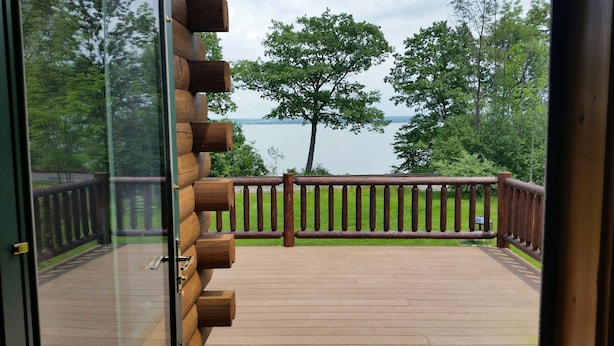 Une terrasse en bois avec une rambarde, donnant sur un lac et des arbres.