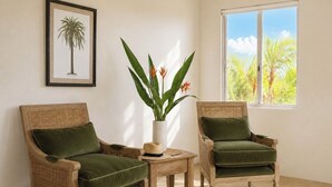 Two wicker armchairs with green cushions, a small table with a plant, and a framed picture of a palm tree on the wall. - The VILLA with THE VIEW - Villa 4 Island Point Road. (Port Douglas)