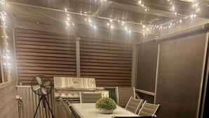 An outdoor patio with a dining table, chairs, a grill, and string lights. - Family Getaway in Moonta Bay (Moonta Bay)