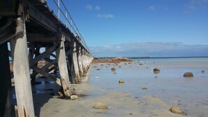 A wooden pier extending into calm waters with scattered rocks on the beach. - Family Getaway in Moonta Bay (Moonta Bay)