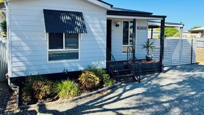 A white mobile home with a covered porch, a small garden, and a sign reading "Atlantic Village." - Family Getaway in Moonta Bay (Moonta Bay)