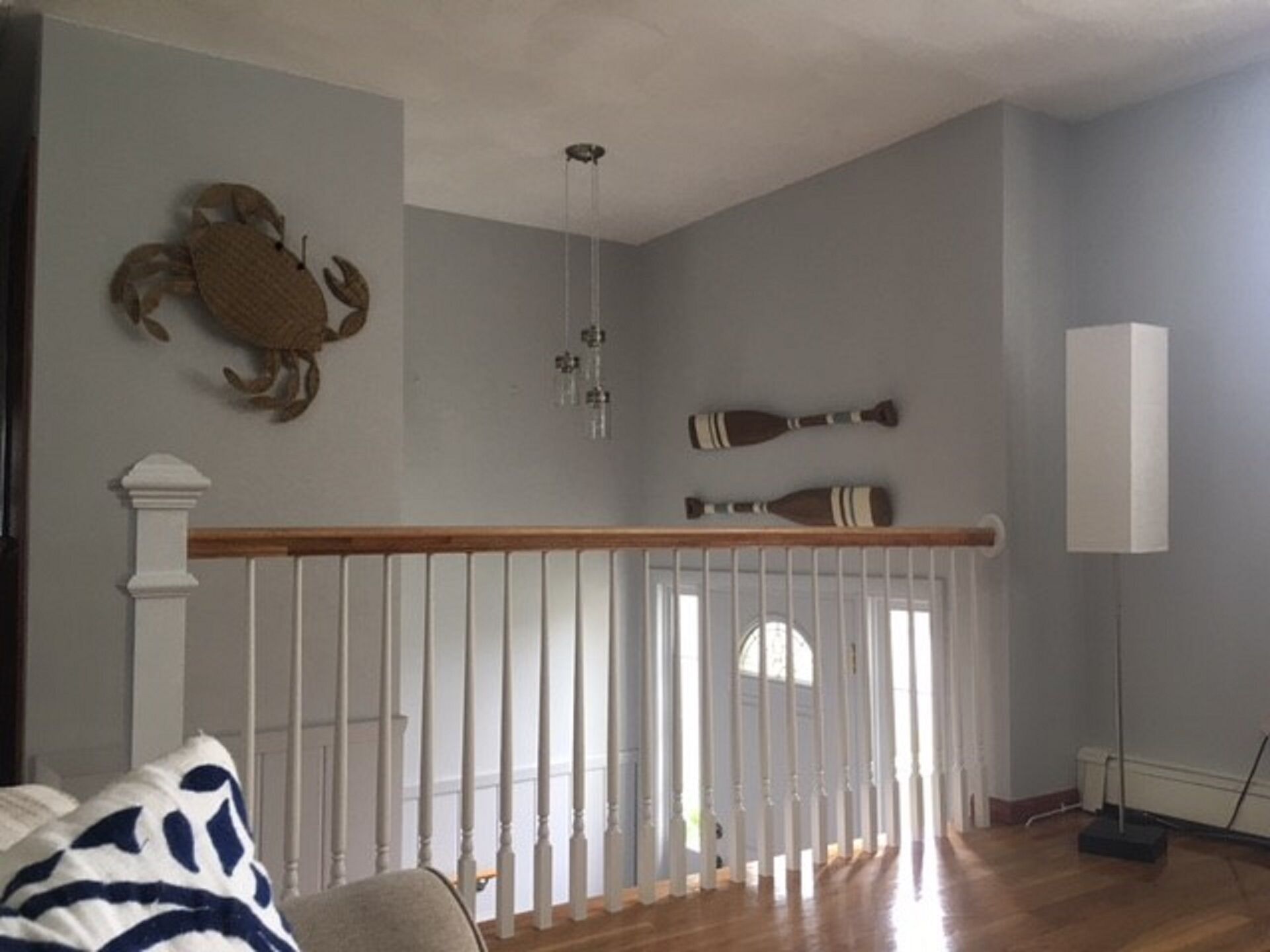 A room with a wooden floor, white railing, and a large window.