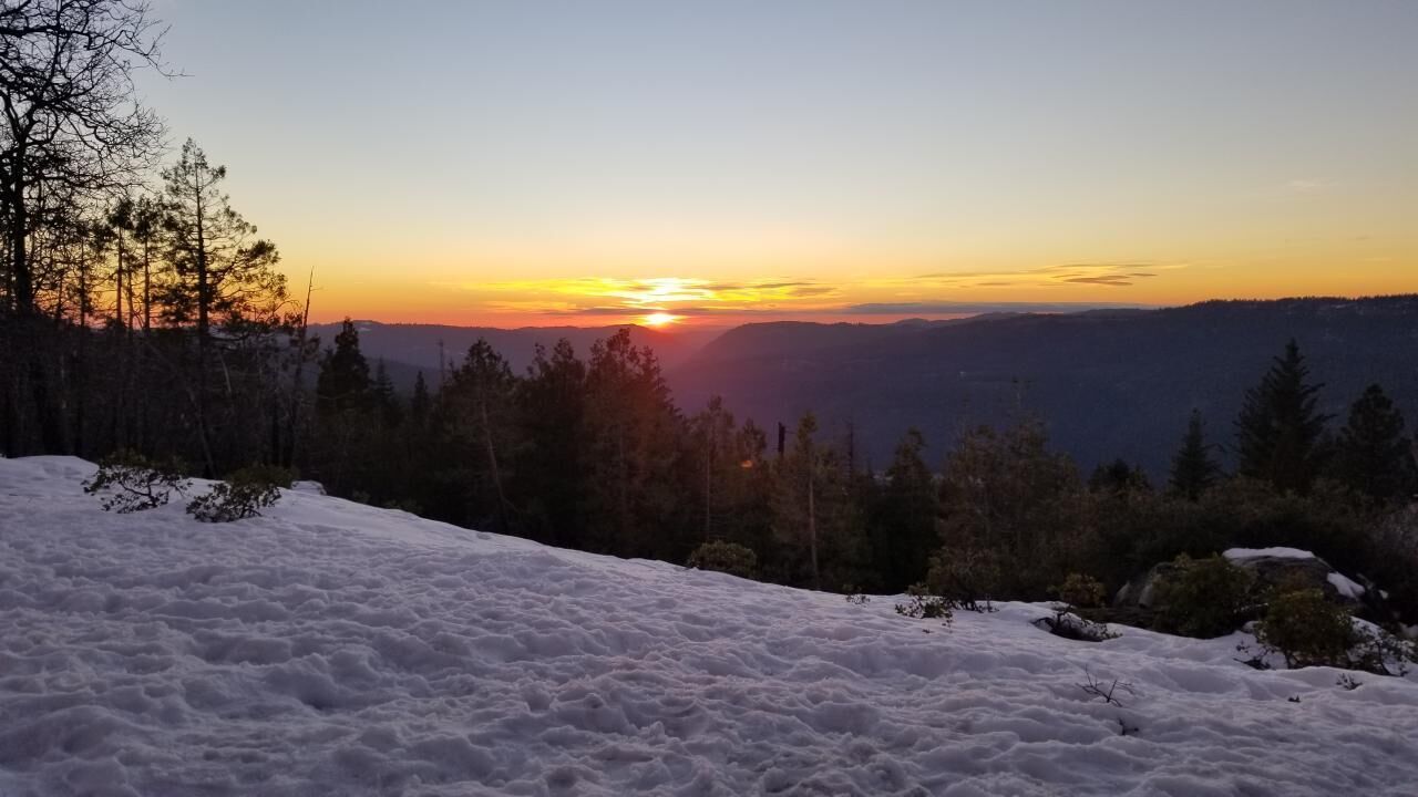 A snowy landscape with a sunset in the background.