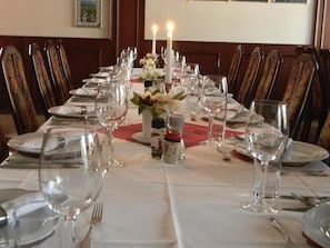 A dining table set for a meal with chairs, candles, and a centerpiece.