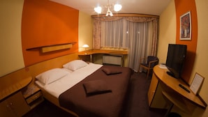 Une chambre d’hôtel avec un lit double, un bureau avec une télévision et une chaise.