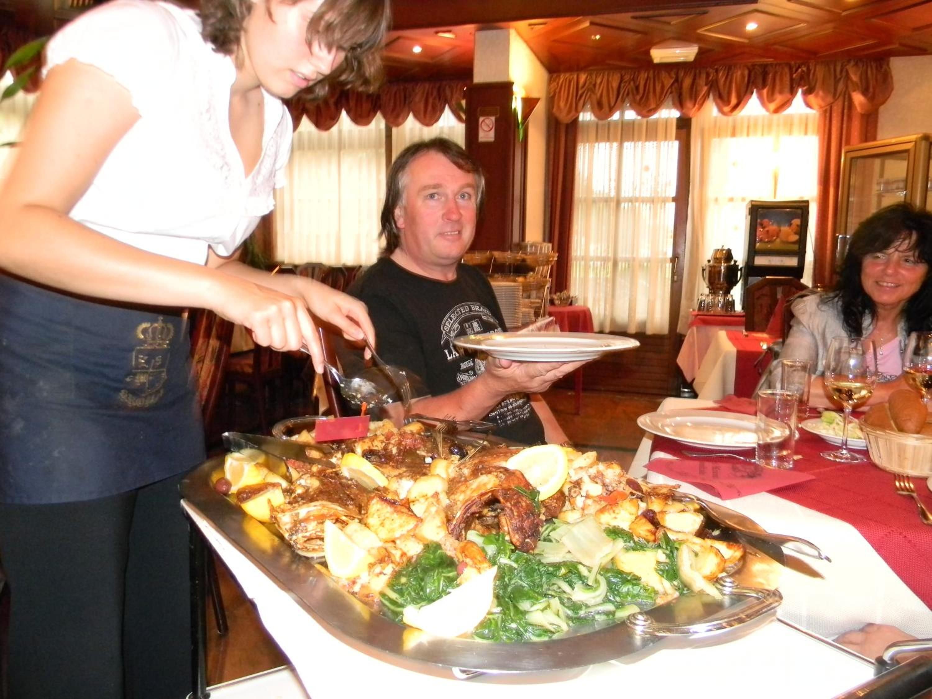 A dining area with a buffet setup, including a variety of dishes and a waiter serving food.