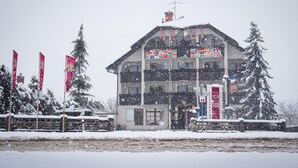 Un hôtel à étages, orné de drapeaux et entouré d’un paysage enneigé.