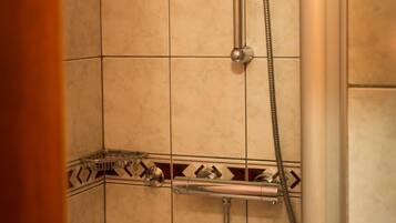A shower area with a handheld showerhead and a vertical showerhead.