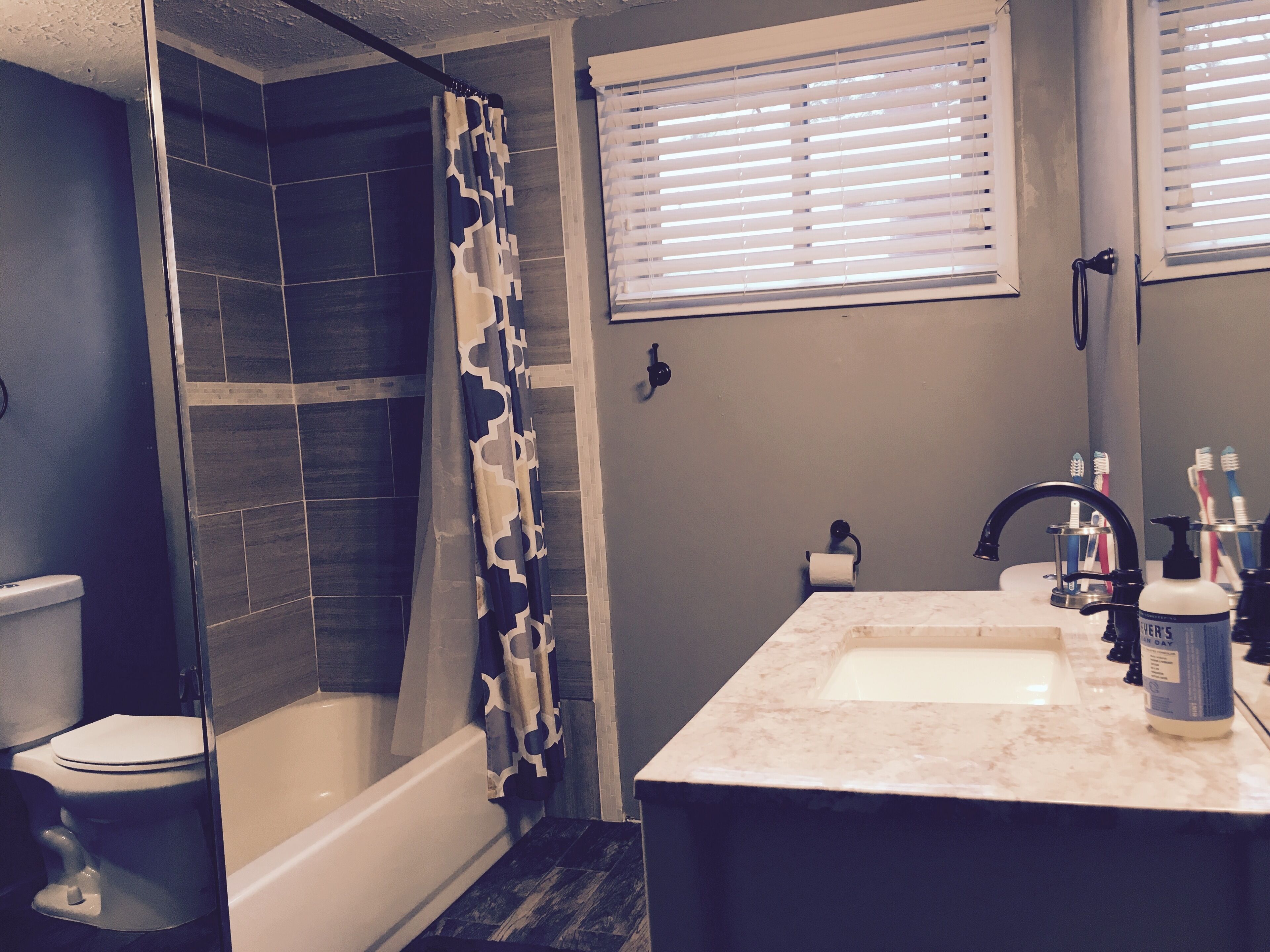 Ein Badezimmer mit Dusche, Toilette, Waschbecken und Fenster.