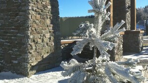 A stone building with a wooden structure in the background, a sign reading "Opening Eagle Lodge," and a snow-covered tree in the foreground. - 🎿 Ski-In\Out Penthouse. Sunrise 🌅 Mtn ⛰️ Views. Snowshoe’s Most Luxurious Lodge 🌅 (Snowshoe)