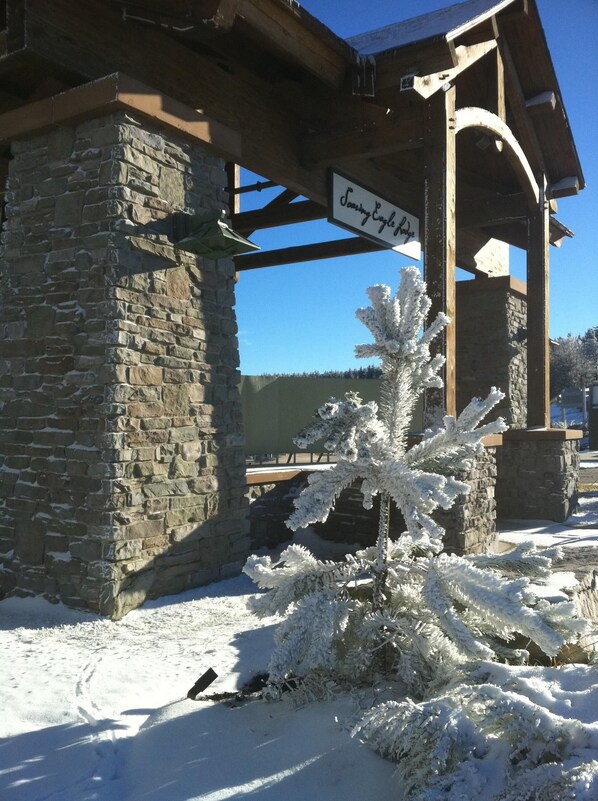 A stone building with a wooden structure in the background, a sign reading "Opening Eagle Lodge," and a snow-covered tree in the foreground. - 🎿 Ski-In\Out Penthouse. Sunrise 🌅 Mtn ⛰️ Views. Snowshoe’s Most Luxurious Lodge 🌅 (Snowshoe)