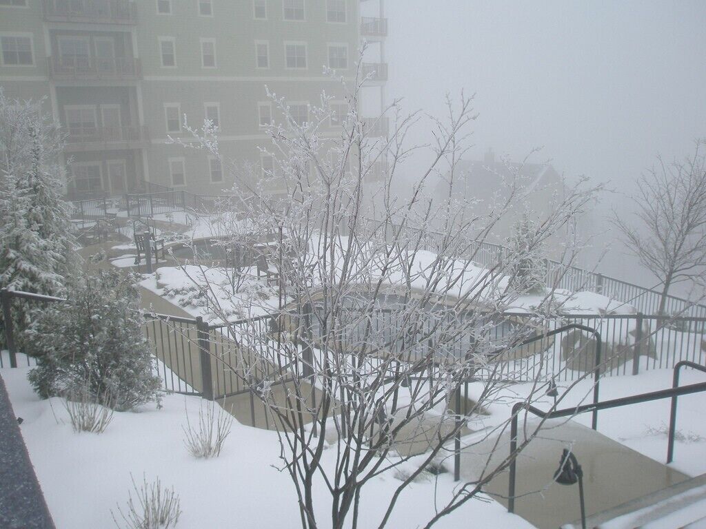 A snowy outdoor area with a staircase, a railing, and a building in the background.
