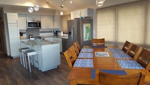 Una cocina moderna con una isla central, armarios blancos y electrodomésticos de acero inoxidable.
