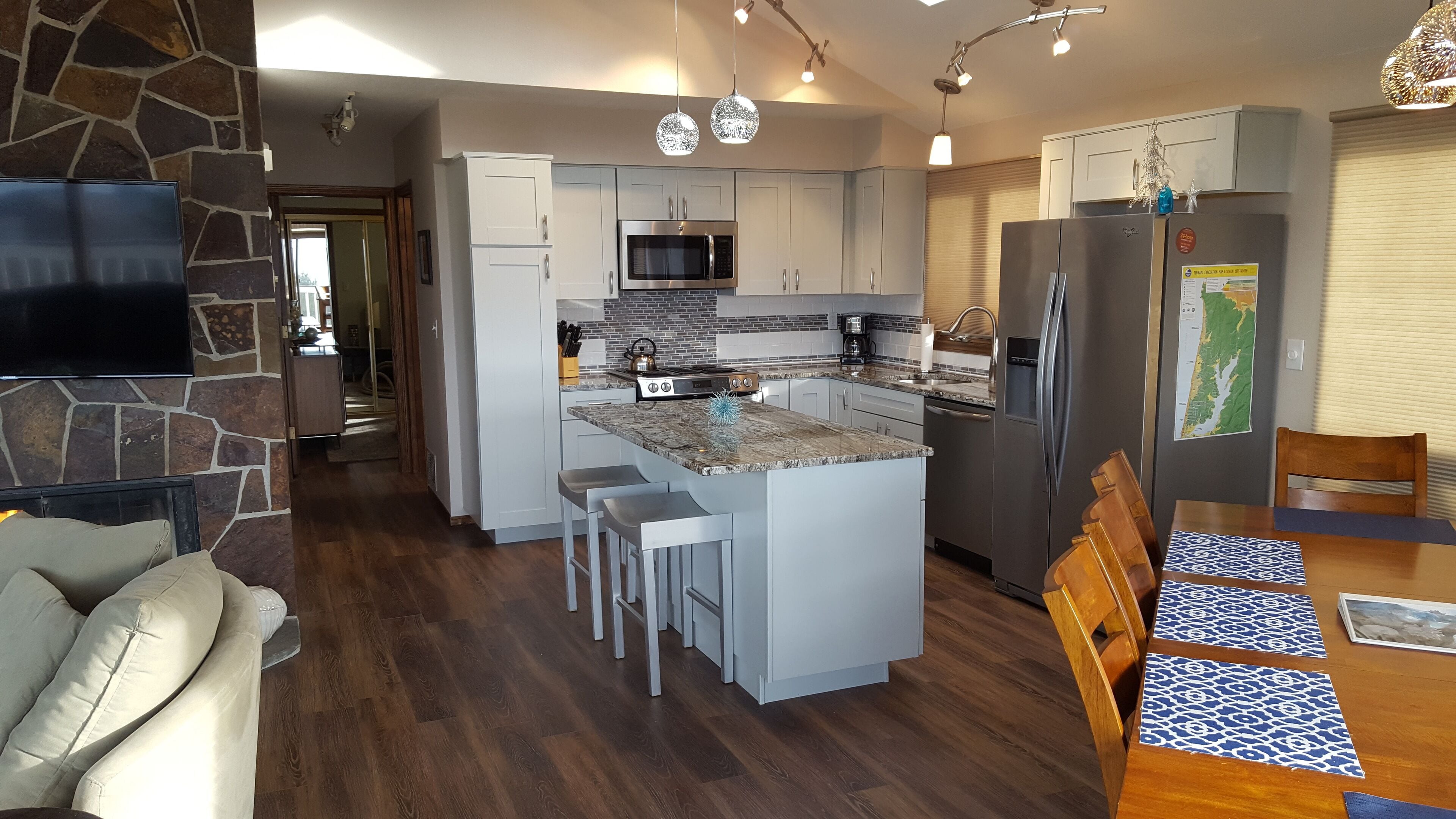 Una cocina moderna con una isla central, electrodomésticos de acero inoxidable y un comedor con mesa y sillas de madera.