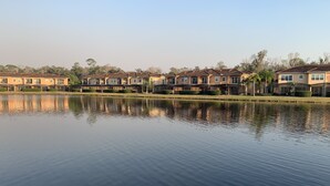 Une rangée de maisons identiques, avec un lac paisible en premier plan.