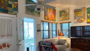 Una habitación luminosa con cama, sofá, televisor y obras de arte en las paredes.