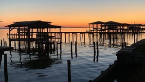 Un muelle con estructuras de madera que se adentran en aguas tranquilas al atardecer.