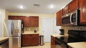 A modern kitchen with stainless steel appliances, wooden cabinets, and a tiled backsplash. - Budget friendly villa; Sleeps 8 w/saltwater pool! Villa Luisa - SWFL Rentals (Cape Coral)