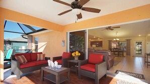 A spacious living area with wicker furniture, a ceiling fan, and a view to the outside. - Budget friendly villa; Sleeps 8 w/saltwater pool! Villa Luisa - SWFL Rentals (Cape Coral)