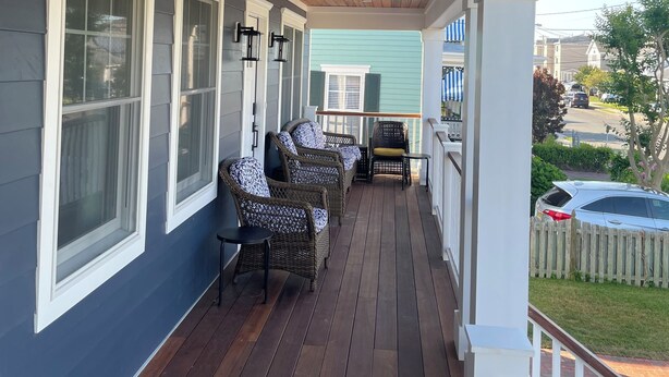 A covered porch with dark wooden flooring, white railings, and wicker furniture. - Cape May Vacation Rentals- Great Location! Just BLOCK & 1/2 to BEACH and TOWN!  (Cape May)