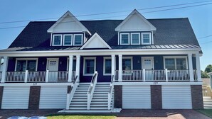 A two-story house with a covered porch, a garage, and a staircase leading to the entrance. - Cape May Vacation Rentals- Great Location! Just BLOCK & 1/2 to BEACH and TOWN!  (Cape May)