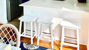 A modern kitchen with white cabinets, a stainless steel refrigerator, a microwave, and a stove. There are three white bar stools and a ceiling fan. - Cape May Vacation Rentals- Great Location! Just BLOCK & 1/2 to BEACH and TOWN!  (Cape May)