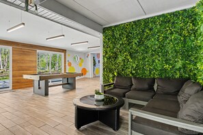 Un espace intérieur moderne comprenant une table de billard, un canapé et un mur végétal.
