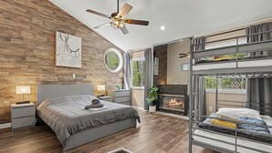 A modern bedroom with a bed, a ceiling fan, a fireplace, and a bunk bed. - Modern Creek-front House with Rooftop and Volleyball court (Bushkill)