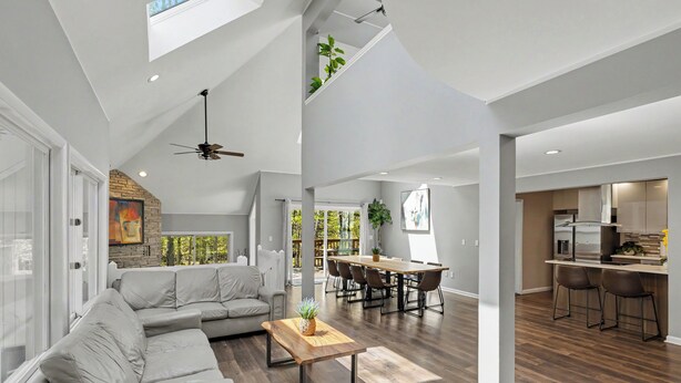 A spacious living area with a sofa, dining table, and kitchen in the background. - Modern Creek-front House with Rooftop and Volleyball court (Bushkill)