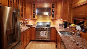 A kitchen with wooden cabinets, a stainless steel refrigerator, a stove, and a sink.