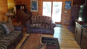 A cozy cabin interior with a wooden interior, a leather sofa, a coffee table, and a television.