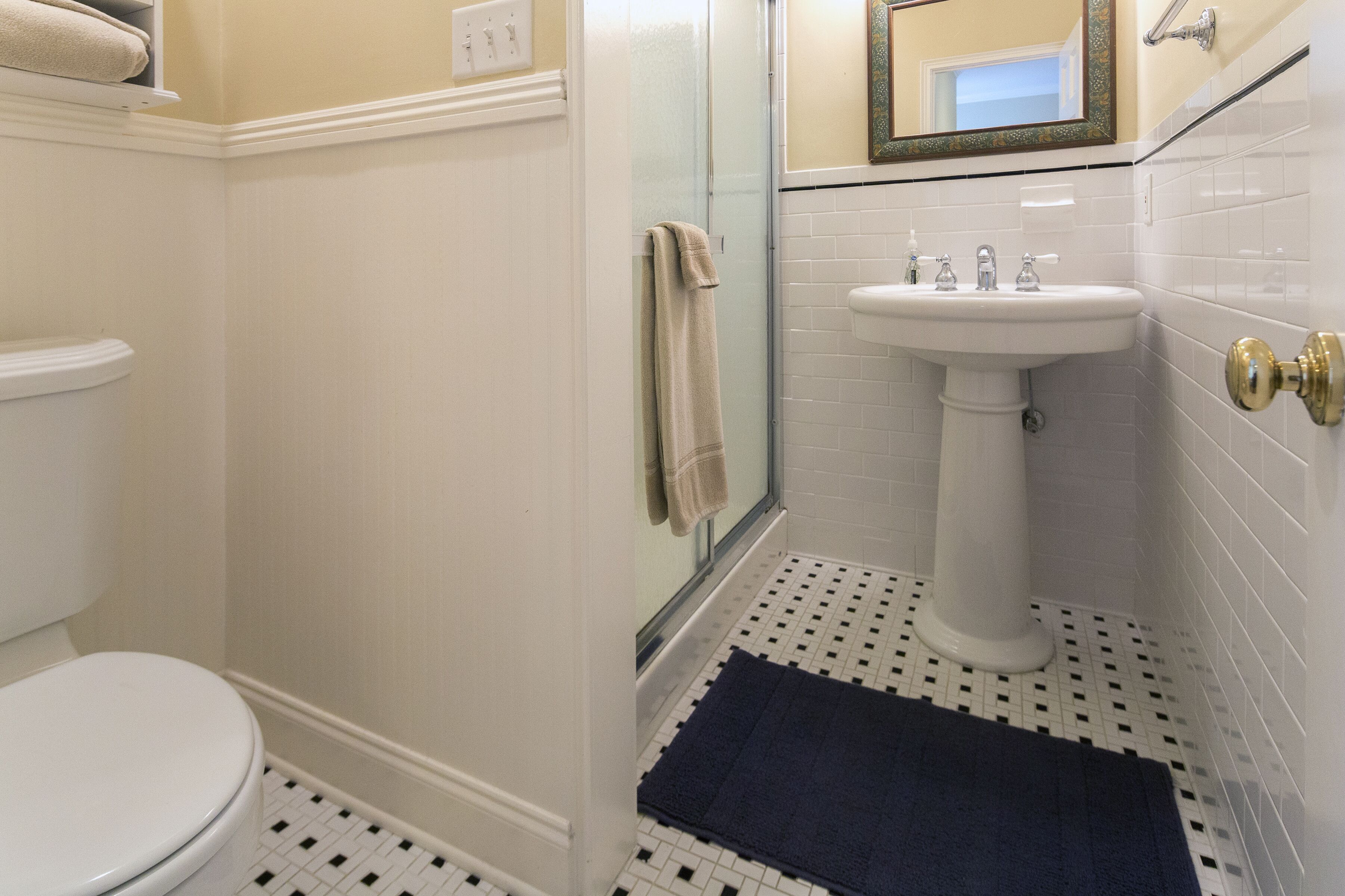 A bathroom with a toilet, a sink, and a shower area.